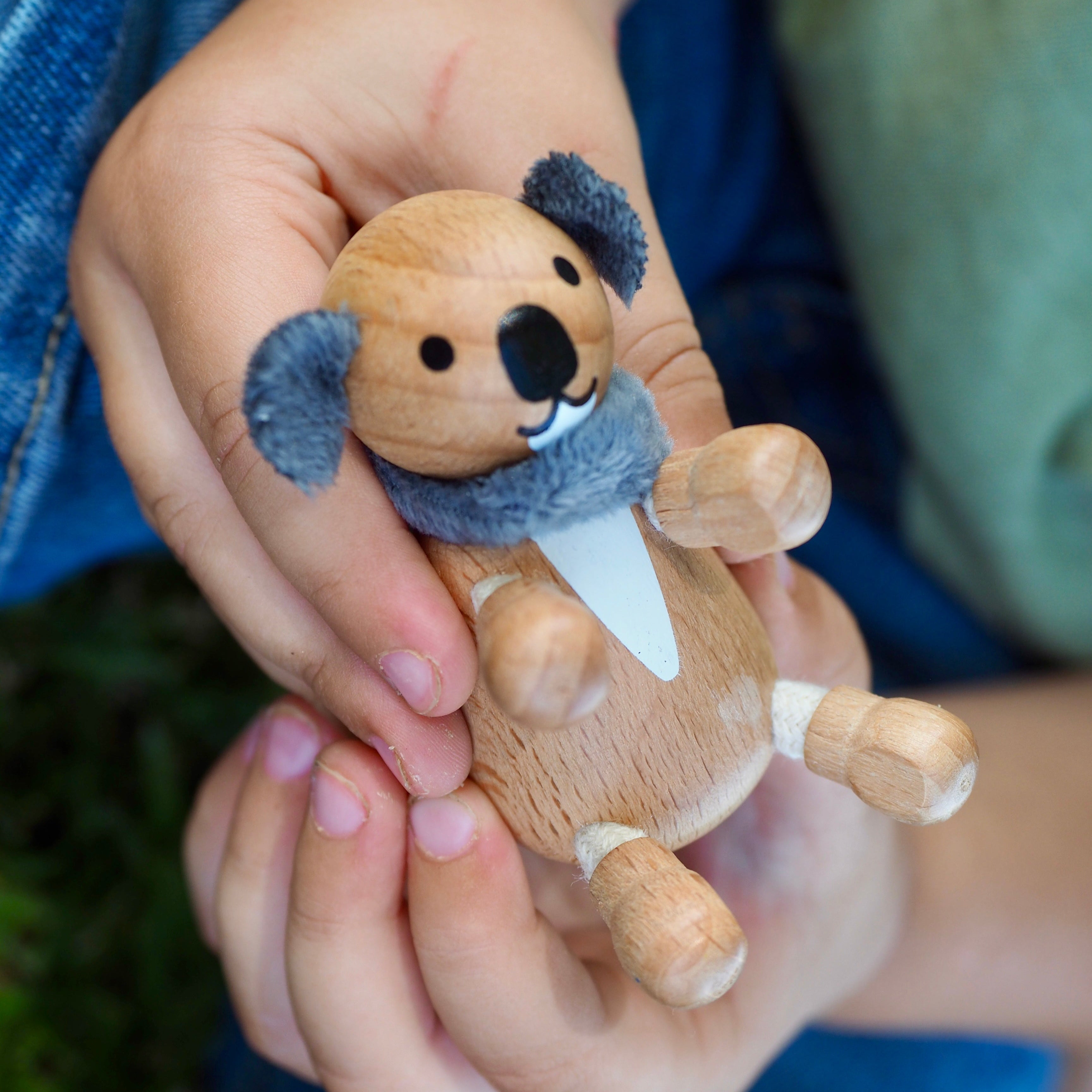 Wooden koala toy held in a child's hand.