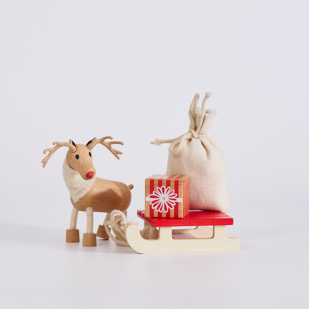 Wooden reindeer with a red sled and gift box on a white background