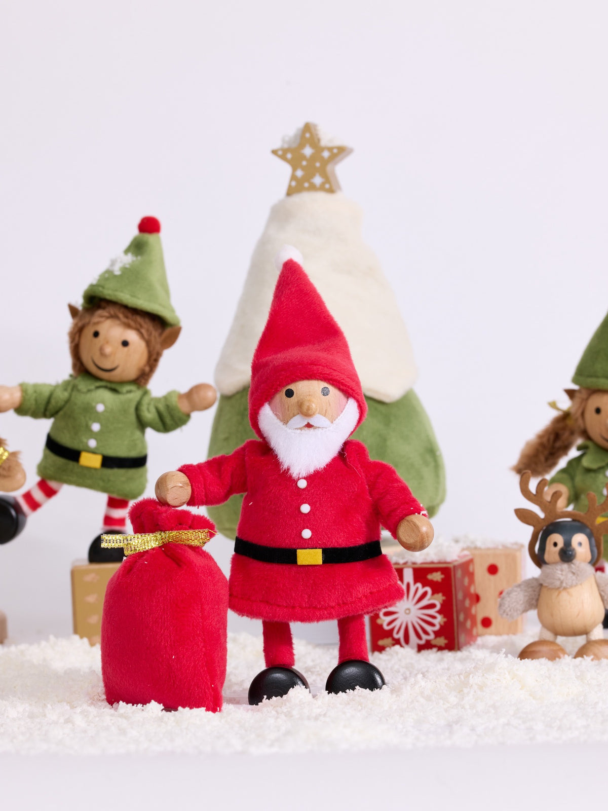 Cheery Santa standing beside a red sack and Christmas tree in a snowy festive scene