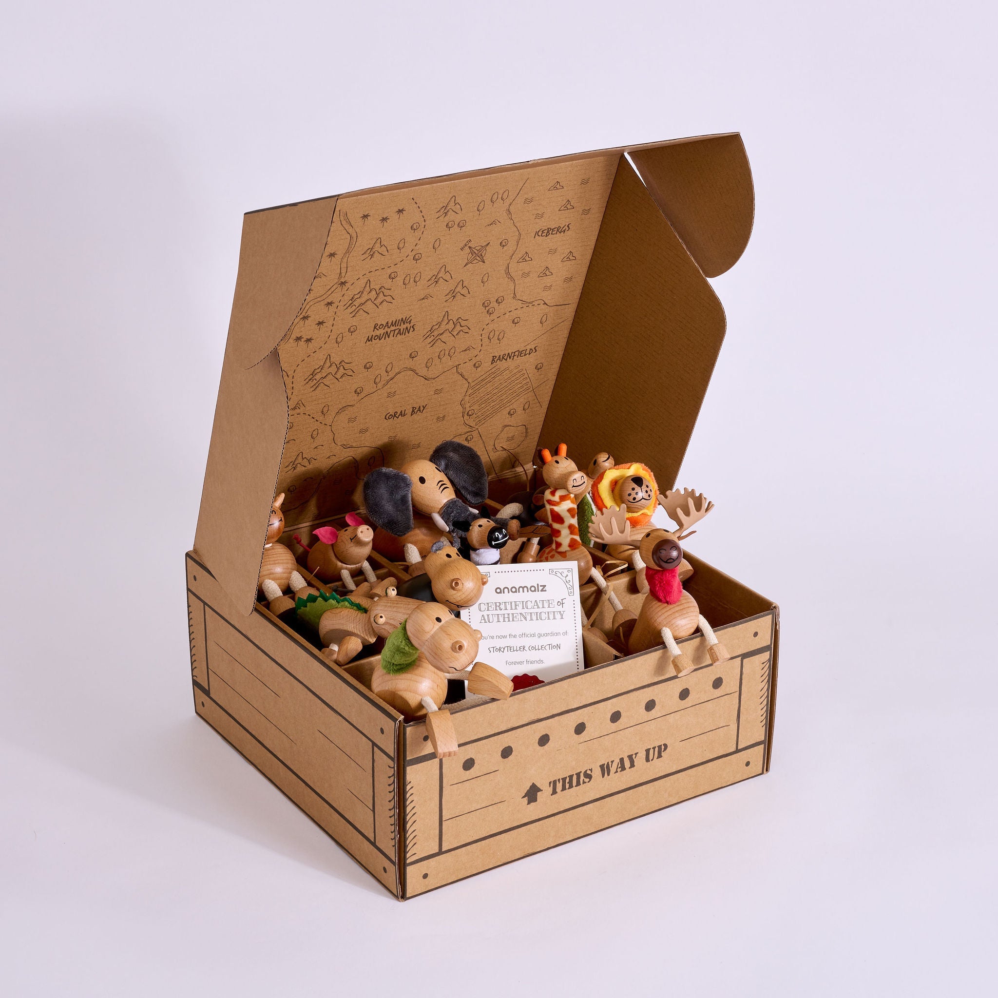 A cardboard gift box with the words 'THIN WAY UP' printed on the front, shown open on a light gray studio background. Inside the box are several small wooden animal figurines and a small white card.