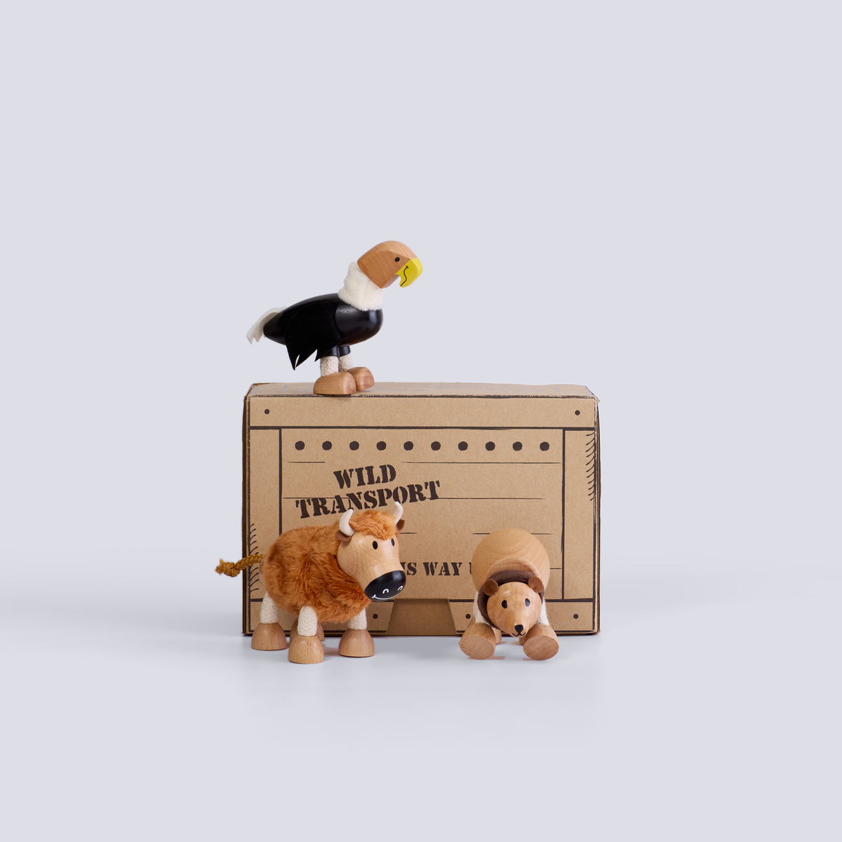 Wooden animal figurines on a cardboard box labeled 'Wild Transport' against a white background