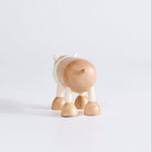 A wooden polar bear toy facing backwards, standing upright on a white background.