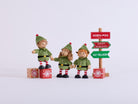 Three Cheeky Elves playing around present blocks beside the North Pole sign